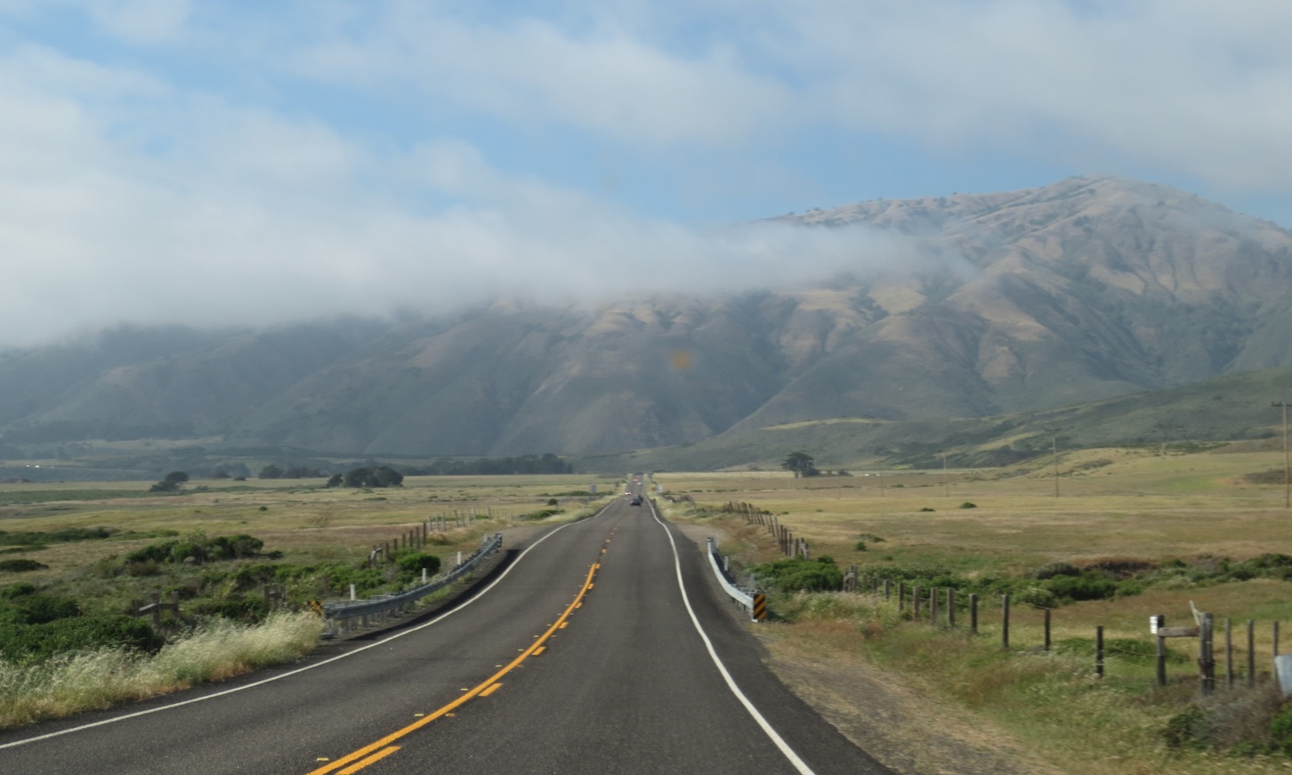 The road ahead with the mountains and clouds in the distance