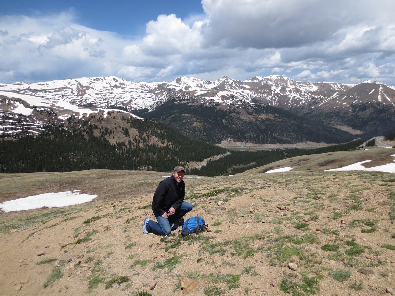 Matt Makai kneeling in front of snow capped mountains in the distance.